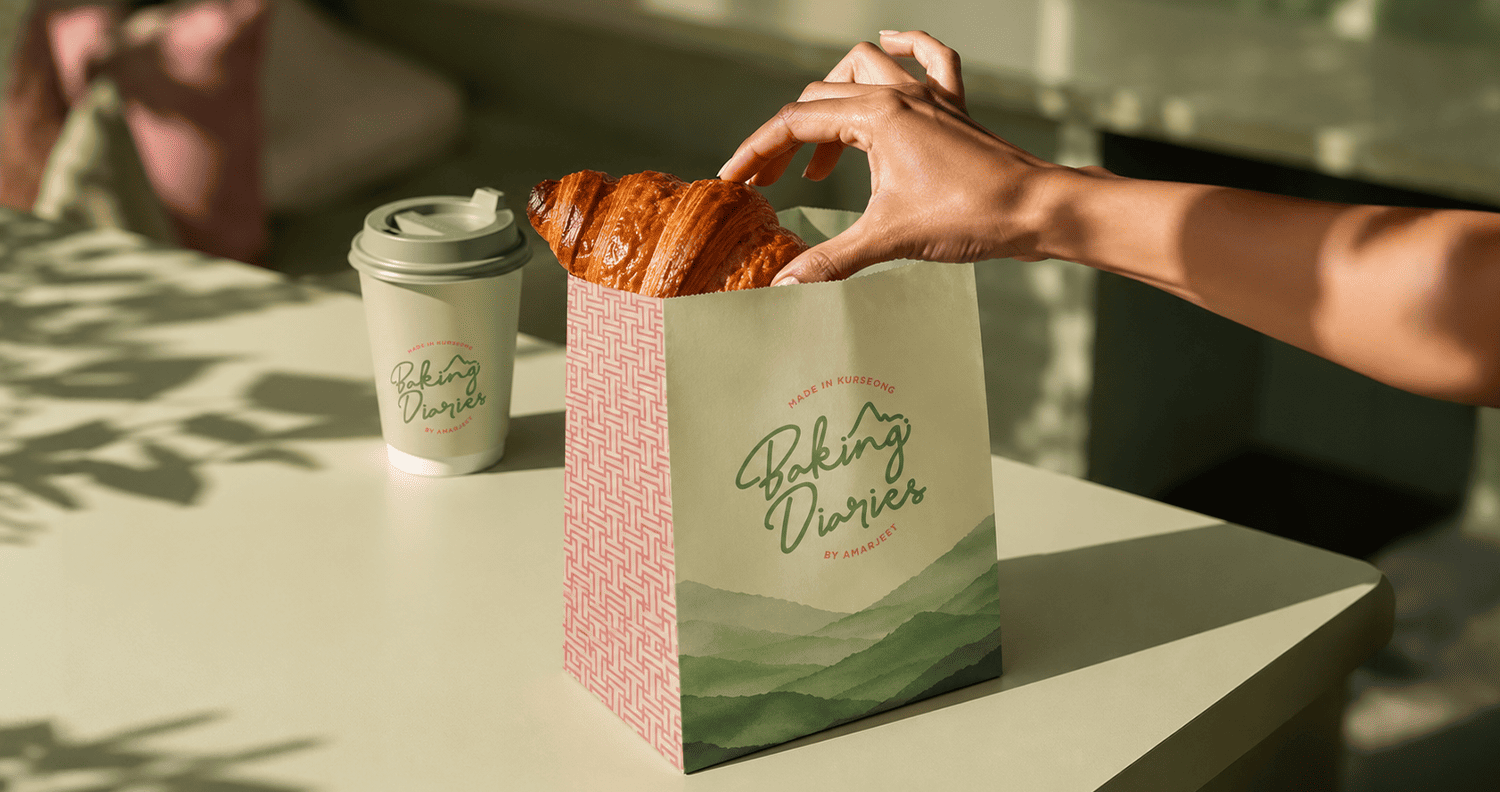 Branded Baking Diaries paper bag and takeaway coffee cup on a caf&eacute; table