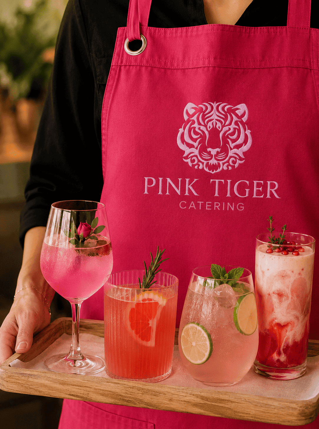 Pink Tiger branded apron — person holding cocktails tray