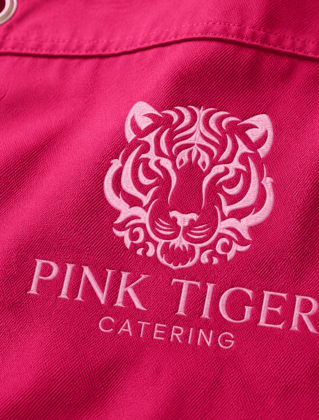 Pink Tiger embroidered logo close-up on pink apron